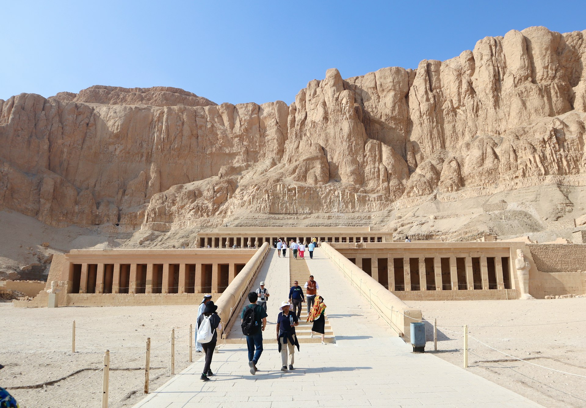 a group of people walking across a bridge in front of a mountain